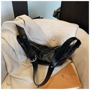 Detail of black leather dumpling bag with silver zipper and adjustable shoulder strap