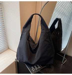 Close-up of a black canvas hobo tote bag with multiple zippers in a modern home setting