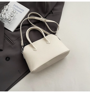 Dettaglio borsa a mano beige in pelle grana con manici tondi e tracolla regolabile