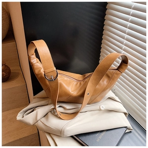 Close-up of brown leather dumpling bag showing smooth texture and silver metal buckle