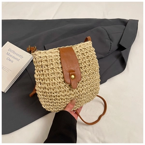 Detail of woven straw bucket bag with brown leather flap and golden button closure