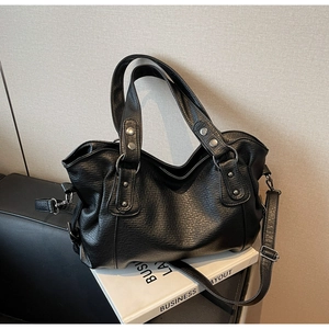 Close-up of black pebble leather tote with silver rivets and adjustable shoulder strap