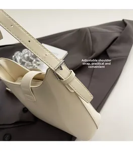 Gros plan d'un sac crème avec bandoulière réglable et boucle métallique argentée