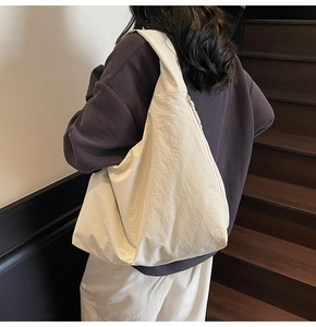 Detailed side view of a large white nylon tote bag worn over the shoulder by a model