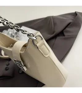 Détail latéral du sac seau en cuir blanc cassé avec chaîne argentée et boucle logo