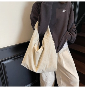 Detail of minimalist oversized tote bag in cream nylon texture worn on shoulder