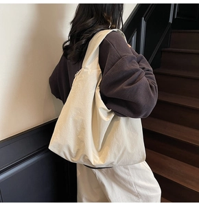 Detailed side view of off-white large capacity tote bag shown on a shoulder