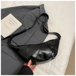 Detail of black leather dumpling bag with glossy finish and adjustable wide shoulder strap