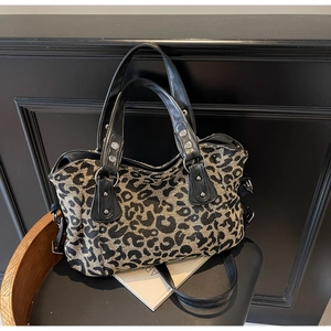 Detail shot of leopard print travel bag with leather handles and silver metal hardware