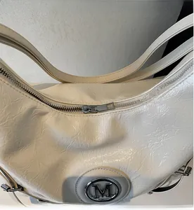 Détail du sac plissé crème avec fermeture éclair métallique fluide et logo M décoratif
