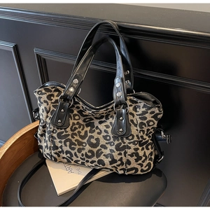 Detail view of leopard print tote bag with silver rivets and black faux leather handles