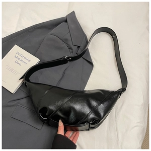 Detail view of the black croissant bag with distinct stitched segments and adjustable strap