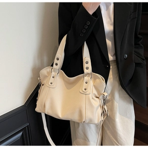 Detail of cream-colored soft leather tote bag with retro rivets and adjustable strap