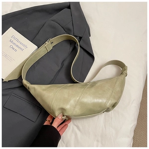 Detail of the light green crescent bag featuring contrast stitching and soft faux leather texture