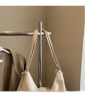 Détail du sac plissé crème avec deux poignées supérieures et connecteurs en anneaux métalliques