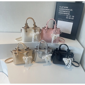 Detail view of colorful PU leather bucket bags with pearl bow charms and knotted handles