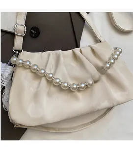 Close-up of minimalist pleated crossbody bag featuring ivory fabric and pearl shoulder strap