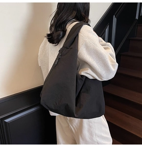 Detail view of black nylon crescent shoulder bag shown on model in a modern interior
