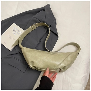 Detail of light green crescent bag with adjustable buckle and soft faux leather texture