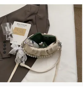 Detail view of cream pleated handbag interior space showing storage capacity and pearl strap