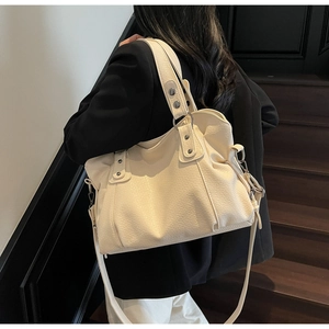 Detail of cream-colored large tote bag with lychee grain texture and silver metal studs