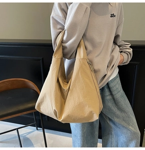 Close-up of beige nylon tote bag showing textured crinkled fabric and wide shoulder strap