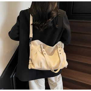 Detail of cream white tote bag featuring pebble grain texture and silver metal hardware