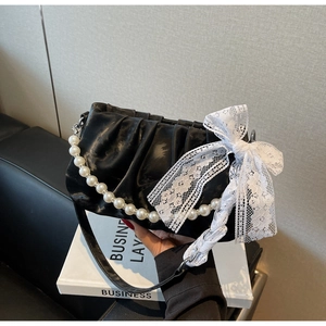 Close-up of black pleated cloud bag with white pearl handle and delicate lace bow detail