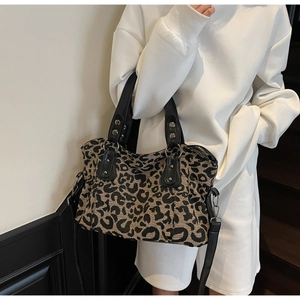 Detail of leopard print canvas tote bag with black leather handles and silver rivets