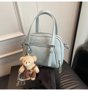 Dettaglio borsa azzurra con cerniere e ciondolo a forma di orsetto di peluche