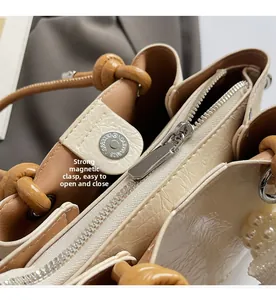 Detail view of strong magnetic snap and zip closure on cream pleated leather handbag