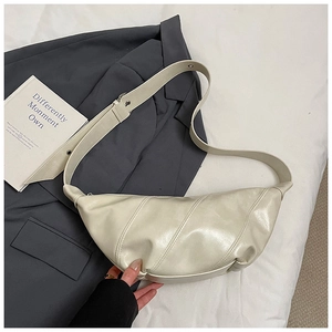 Close-up of cream white dumpling bag with glossy pleated texture and wide strap