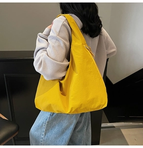 Detail view of a bright yellow large-capacity canvas tote bag on a fashion model
