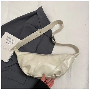 Detailed view of beige dumpling bag texture with adjustable strap on fabric background