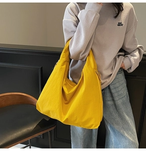 Detail of a bright yellow high-capacity tote bag styled with casual purple waffle sweatshirt