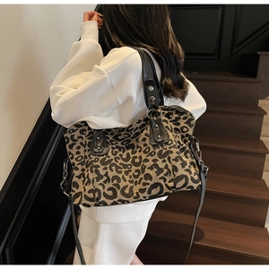 Detail of leopard print tote bag featuring black leather handles and silver studs decoration
