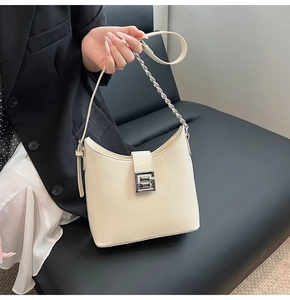 Close-up of cream leather shoulder bag with silver G buckle and chain strap detail
