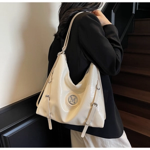 Détail du cabas en cuir verni blanc cassé avec logo M argenté et boucles latérales chic