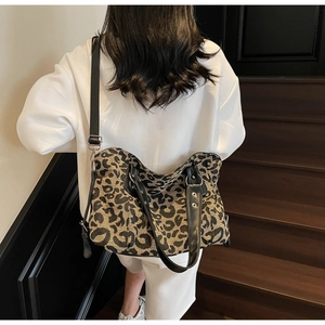 Detailed view of large leopard print tote bag featuring black leather handles and canvas texture
