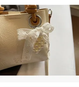 Close-up of off-white bucket bag with pleated texture, lace bow, and pearl strawberry charm