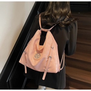 Détail d'un sac à dos rose en cuir verni avec logo M argenté et boucles en métal