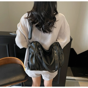 Detailed view of a black lychee texture hobo bag with silver studs on a female model