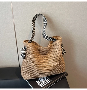 Détail d'un sac cabas en paille tissé avec des anses en tissu à rayures noir et blanc