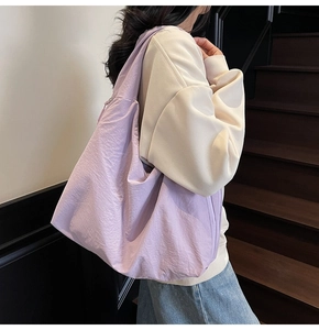 Detailed side view of purple pleated nylon tote bag worn by a model in a minimalist style