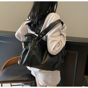 Side view of large black lychee leather tote bag with metal eyelet strap on model