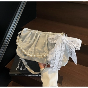 Detail of silver pleated satin bag with lace bow and elegant pearl handle strap
