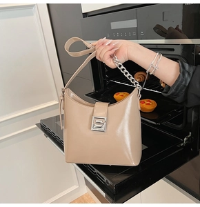 Detail of glossy beige leather hobo bag with silver square buckle and chunky chain strap