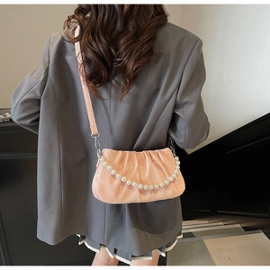 Detail of light pink pleated cloud bag with pearl strap and long shoulder strap