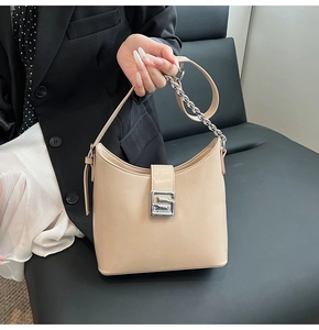 Detail view of beige leather underarm bag with silver square buckle and chain strap