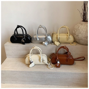 Sacs Boston miniatures en cinq couleurs avec breloques cœur sur des marches en pierre